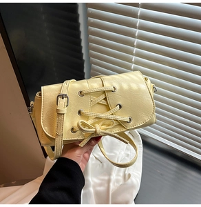 Detail of cream shoulder bag with corset-style lace-up design and silver eyelets
