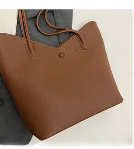 Detailed macro view of the brown litchi pattern leather texture and magnetic buckle of tote