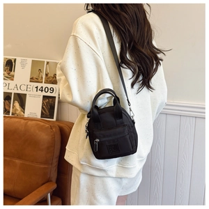 Detailed back view of a black waterproof nylon crossbody bag worn by a fashion model