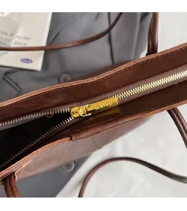 Detailed close-up of premium gold zipper and leather texture on a brown tote bag