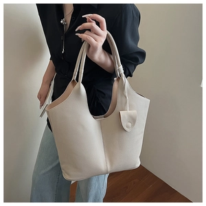 Detail of beige litchi grain bucket bag with U-shaped opening and mini pouch accessory