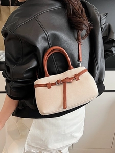 Fashionable beige canvas bucket bag with brown leather trim and adjustable shoulder strap