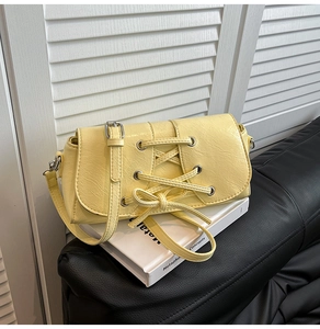 Detail of light yellow PU leather crossbody bag with drawstring design and silver hardware
