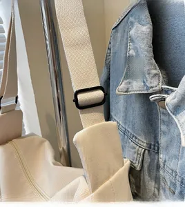 Detail of adjustable thick woven shoulder strap and metal buckle on canvas crossbody bag