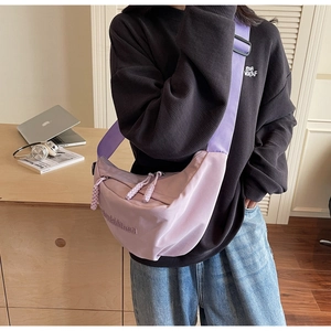 Close-up of light purple nylon crescent bag with wide strap and detailed embroidery