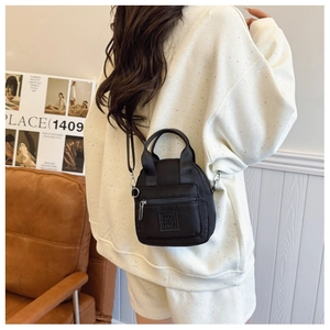 Detailed back view of a black waterproof nylon crossbody bag held by a model
