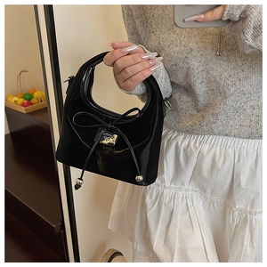 Détail du sac à main noir brillant avec nœud élégant et pendentifs sphériques en argent
