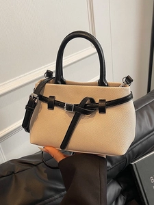 Beige textured mini bucket bag with black handles and crossbody strap, elegant 2026 style