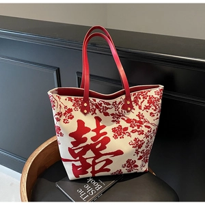 Close-up of a red and white canvas tote bag with a Xi character on a chair
