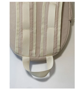 Detail of reinforced nylon webbing and sturdy bottom handle on a beige backpack