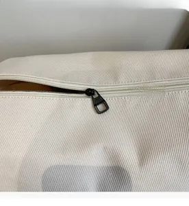 Close-up of smooth black metal zipper on beige canvas crossbody bag with twill texture