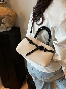 Chic beige woven bucket bag with black leather straps shown on a model's back