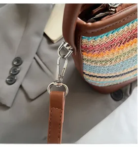 Dettaglio dei ganci metallici argentati e cuciture su una borsa a secchiello tessuta