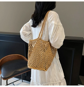 Detail of handwoven hollow mesh knit tote bag in natural khaki on a female model