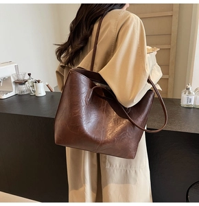 Detailed view of the dark brown leather tote bag texture and slim shoulder straps