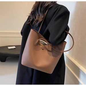 Detail of a brown lychee pattern leather tote bag showing texture and slim shoulder strap
