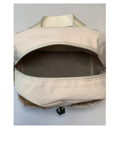 Top view of beige nylon backpack interior with drawstring toggle and webbing handle