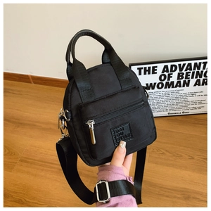 Close-up of waterproof black nylon mini bag with dual handles and silver zipper details