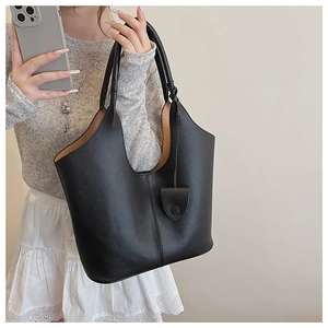 Detail shot of black pebbled leather bucket bag with contrasting tan interior and long strap