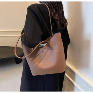 Brown leather tote bag side view on model showing spacious bucket design and shoulder strap