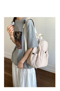 Detail of light cream nylon backpack featuring drawstring side pockets and a sleek design
