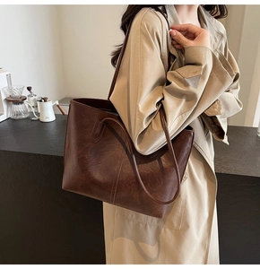 Detail view of large dark brown leather tote bag with fine stitching and slim straps