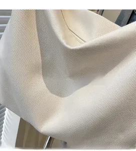Detail of off-white tote bag showing textured knit fabric and top zipper closure