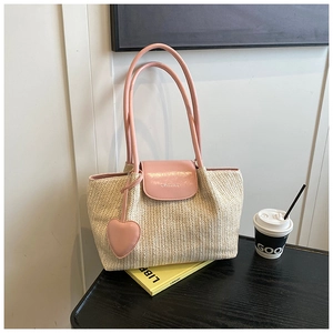 Detailed texture of handwoven straw tote with pink leather handle and heart charm accessory