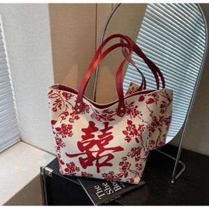 Detail of canvas tote bag featuring traditional red Xi character and leather handles