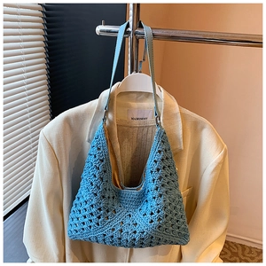 Détail du sac à bandoulière en tricot bleu avec sangle en cuir sur un blazer