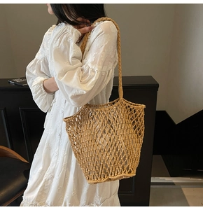 Detailed close-up of a large beige hand-woven knit tote bag with mesh cutout texture