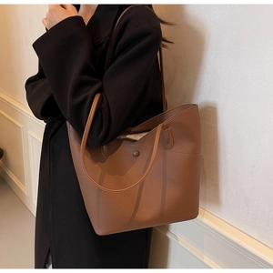 Brown lychee leather tote bag shown on model with black coat for daily commute styling