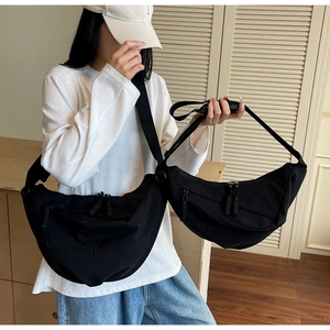 Detail of embossed logo on black nylon crescent bag with adjustable shoulder strap