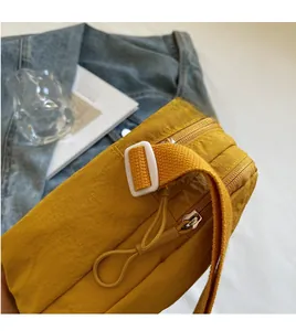 Vue détaillée d'un sac bandoulière en nylon jaune avec sangle réglable et fermeture éclair