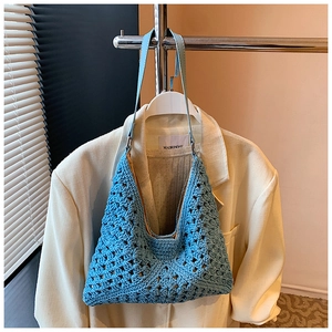 Détail d'un sac hobo en crochet bleu clair avec motifs ajourés et bandoulière en cuir