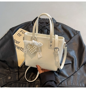 Détail du sac à main en cuir plissé blanc avec breloque cœur perle et nœud dentelle