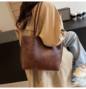 Detailed view of deep brown vintage leather tote bag with vertical stitching and slim handles