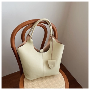 Detailed view of cream-colored bucket bag with lychee grain leather on a wooden chair