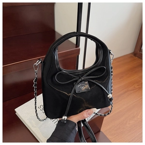 Détail d'un sac en nylon noir avec grand nœud, chaînes argentées et étiquette logo