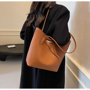 Detail view of caramel tote bag showing large pebble grain leather and thin shoulder straps