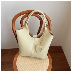 Detail of light yellow pebbled leather tote bag placed on a classic wooden woven chair