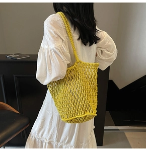 Detail of bright yellow hand-woven hollow mesh tote bag with wide shoulder strap
