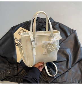 Détail du sac seau crème en similicuir plissé avec breloque cœur et perles