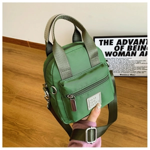 Close-up of green waterproof nylon crossbody bag with zipper pocket and broad strap