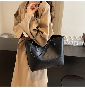 Classic black leather tote bag shown on model with shoulder strap and minimalist stitching