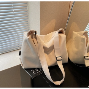 Detail of off-white canvas tote bag with wide strap and zipper on book stand