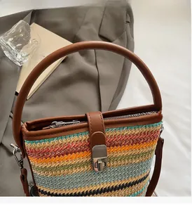 Dettaglio della borsa a secchiello intrecciata colorata con manico in pelle marrone e fibbia