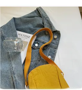 Gros plan sur le sac bandoulière en nylon jaune avec sangle épaisse et logo lettré