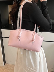 Pink glossy patent leather tote bag with stylish knot details worn by a model