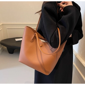 Detail of lychee pattern leather and seamless stitching on a brown tote shoulder bag